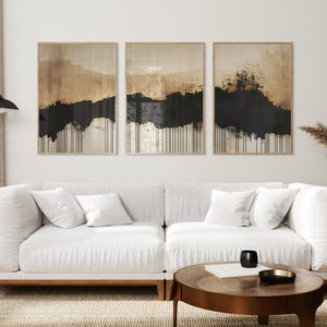 Minimalist abstract triptych featuring earthy beige and black tones with textured brushstrokes and dripping ink effect, evoking Japandi style.