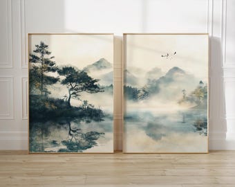 May include: Two framed watercolor paintings depicting a misty mountain landscape with a lake and trees. The left painting features a large tree in the foreground, while the right painting shows a more distant view of the mountains and lake.