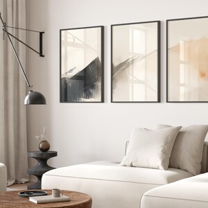 Picture showing a minimalist set of three Japandi-style neutral wall art pieces featuring abstract black and orange brush strokes on a beige background. Available for printing in all standard sizes.