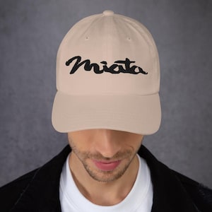 May include: A beige baseball cap with a black embroidered "Miata" logo.