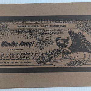 May include: A brown paper menu with black text and illustrations. The menu features the text "NEVER CLOSED 'CEPT CHRISTMAS", "Minutes Away!", and "ZABERERS". Illustrations include a wine glass, grapes, a lobster, and a roast.