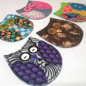 May include: Five colorful fabric owl ornaments with button eyes. Each owl is made from different patterned fabrics and has a unique design.