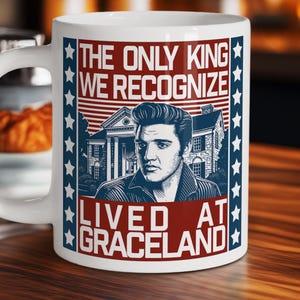 May include: White ceramic mug featuring a portrait of Elvis Presley with the text "THE ONLY KING WE RECOGNIZE LIVED AT GRACELAND." The design includes a red and blue color scheme with stars and stripes.