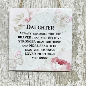 Puede incluir: Un letrero de madera blanco con un diseño floral y el texto "DAUGHTER ALWAYS REMEMBER YOU ARE BRAVER THAN YOU BELIEVE STRONGER THAN YOU THINK AND MORE BEAUTIFUL THAN YOU IMAGINE & LOVED MORE THAN YOU KNOW"