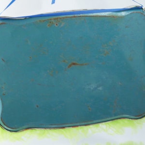 May include: A turquoise blue metal tray with a scalloped edge and a light green fringe around the bottom.