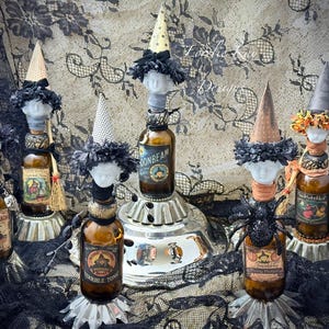 May include: A collection of whimsical bottle toppers, each adorned with a witch-like hat and decorative elements. The bottles feature vintage-style labels and are arranged on a decorative stand, creating a Halloween-themed display.