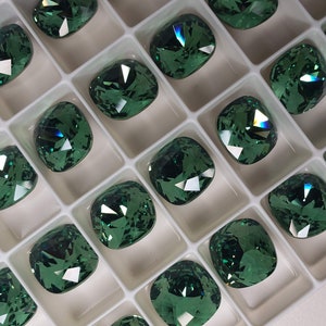 Può includere: Una vista ravvicinata di un vassoio pieno di strass verdi a forma di cuscino. Gli strass sono disposti in file e colonne e hanno una finitura scintillante e iridescente.