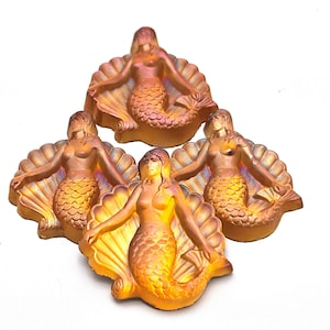 May include: Four gold-toned mermaid figurines, each sitting in a shell, with a detailed, iridescent finish.