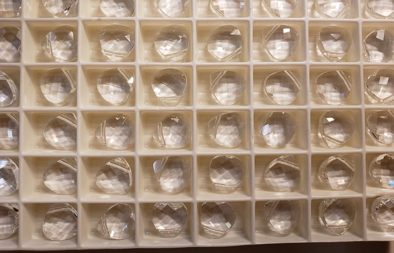 May include: A clear plastic tray filled with clear glass beads. The beads are arranged in a grid pattern and are all the same size and shape.