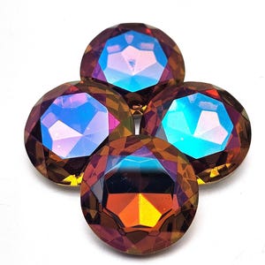 May include: Four iridescent, faceted, round gemstones arranged in a cross shape. The gems have a mix of colors, including orange, purple, and blue, with a golden base. The gems are set against a white background.
