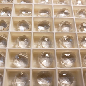 May include: A tray of clear, faceted, teardrop-shaped crystals.