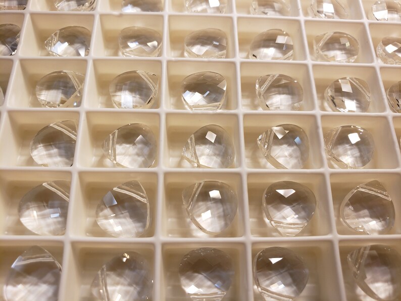 May include: A tray of clear, faceted, teardrop-shaped crystals.