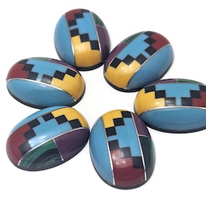 May include: Six oval-shaped turquoise cabochons with geometric patterns in black, red, yellow, and green. The cabochons are set in silver.