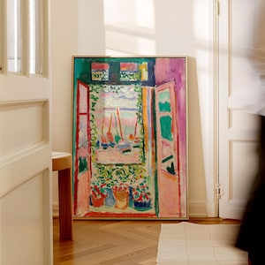 Könnte beinhalten: Ein gerahmtes Gemälde, das eine farbenfrohe Fensterszene mit Blick auf Boote auf dem Wasser zeigt. Das Fenster ist geöffnet und auf dem Fenstersims stehen Pflanzen in Töpfen. Das Gemälde ist in einem hellen Holzrahmen.