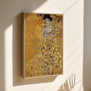 Op de afbeelding: Een ingelijst schilderij van een vrouw in een gouden jurk met een mozaïekpatroon. De achtergrond is ook goud met een mozaïekpatroon.