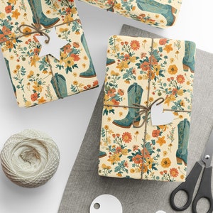May include: Gift-wrapped presents with a floral and cowboy boot pattern. The wrapping paper features a cream background with orange, yellow, and blue flowers and boots. Each package is tied with twine and a white tag. A spool of twine and scissors are also visible.
