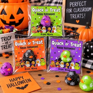 May include: Three clear plastic bags containing rubber ducks for Halloween. Each bag features a colorful card with the text Quack or Treat, Happy Halloween, and From: Nova. The cards display illustrations of ducks in costumes, and the ducks inside are purple, black, and green with various patterns.