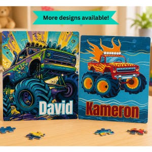 May include: Two rectangular jigsaw puzzles featuring monster truck illustrations. The left puzzle shows a green and purple truck with the name David. The right puzzle shows a red truck with orange flames and the name Kameron. Loose puzzle pieces lie below.