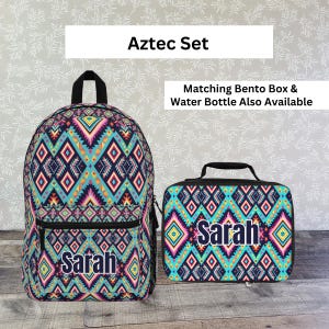 May include: Aztec Set backpack and lunch bag with a colorful geometric pattern. The backpack has a black zipper and the lunch bag has a black handle. Both items are personalized with the name "Sarah". The text "Aztec Set" is at the top.