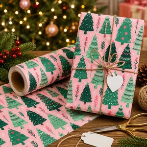 May include: A roll of pink wrapping paper and a rectangular gift box wrapped in the same paper, both featuring a pattern of green Christmas trees and small pink hearts. The gift is tied with brown twine and includes a blank white heart-shaped tag.