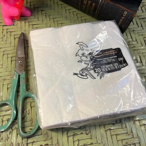 May include: A pack of 20 white Contempo facial tissue napkins. The pack is sealed in plastic and features a cartoon illustration of a bird wearing a hat. The text on the pack reads "Contempo Facial Tissue Napkins 59&cent; 3 Ply Napkins Each 180 sq in (13 1/8 in x 13 1/8 in)."