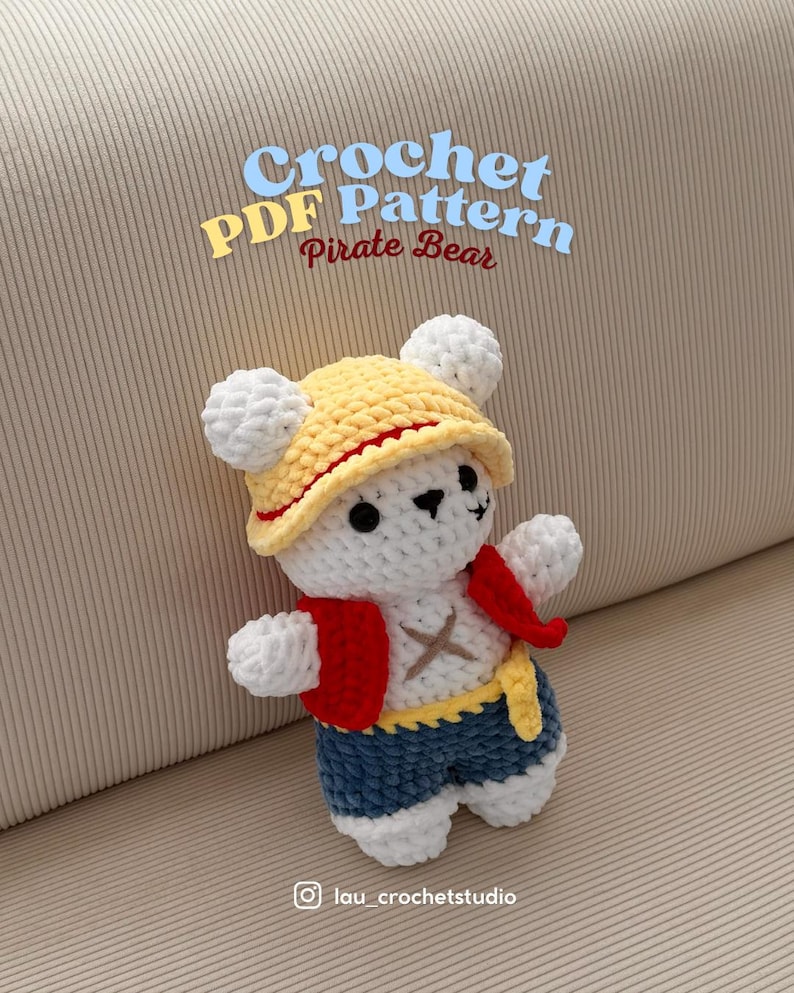K&ouml;nnte beinhalten: Ein geh&auml;kelter wei&szlig;er B&auml;r mit gelbem Hut und rotem Band, roter Weste und blauen Shorts. Der B&auml;r hat einen gelben G&uuml;rtel und ein Kreuz auf der Brust. Der Text auf dem Bild lautet "Crochet PDF Pattern Pirate Bear."