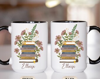 May include: White ceramic mug with a black handle and rim, featuring a floral design with stacked books and the name "Elloise." The books include titles like "Pride and Prejudice" and "To Kill a Mockingbird."