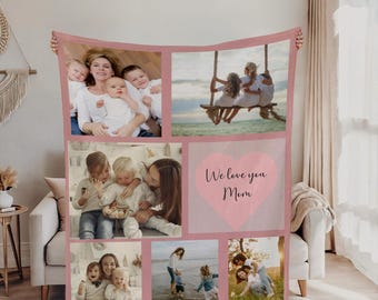 May include: A pink and white personalized photo blanket. The blanket features a collage of family photos and the text "We love you Mom" inside a pink heart. The blanket is held up by unseen hands.
