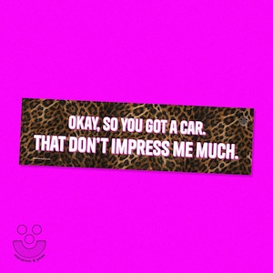 May include: A rectangular bumper sticker with a brown and black leopard print pattern. The text in white with a thin pink outline reads: OKAY, SO YOU GOT A CAR. THAT DON'T IMPRESS ME MUCH. A small logo is visible in the bottom left corner.