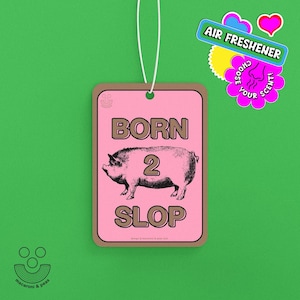 May include: Pink air freshener with a brown border and a white string. The design features a pig illustration with the words "BORN 2 SLOP" in brown text. Additional text reads "AIR FRESHENER" and "CHOOSE YOUR SCENT!"