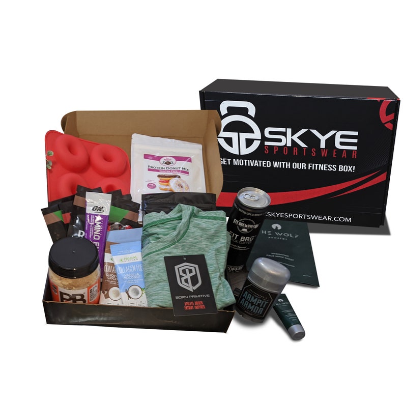 Puede incluir: Una caja de fitness llena de varios art&iacute;culos, incluyendo una camiseta deportiva verde, prote&iacute;na en polvo, un molde para donas y una lata de caf&eacute; fr&iacute;o. La caja tambi&eacute;n contiene productos para el cuidado de la piel y mezcla de prote&iacute;nas. La caja est&aacute; marcada con el texto "SKYE SPORTSWEAR".