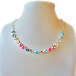 Chain necklace with a a row of 17 small 6 mm diameter crystals in the middle made with austrian crystals.The colour of the crystals is  clear crystal turquoise,neon pink and light rose.There is connected chain on both sides .The necklace is plated in bright silver.The overal length of the necklace is 45cm and has additional extension chain 5cm.A youthful  unique necklace for all occassions.