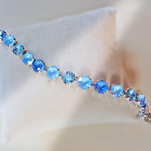Tennis crystal bracelet made with genuine Austrian crystal.This is a full row of 15 crystals medium size 8 mm each in colours aquamarine,sky blue ,soft blue.It is rhodium silver plated nickel free and it is 17cm long including the lobster claw clasp.It coame swith extension chain and  fits average wrist.A sparkling beautful crystal bracelet.