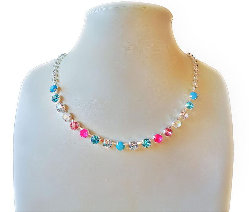 Chain necklace with a a row of 17 small 6 mm diameter crystals in the middle made with austrian crystals.The colour of the crystals is  clear crystal turquoise,neon pink and light rose.There is connected chain on both sides .The necklace is plated in bright silver.The overal length of the necklace is 45cm and has additional extension chain 5cm.A youthful  unique necklace for all occassions.