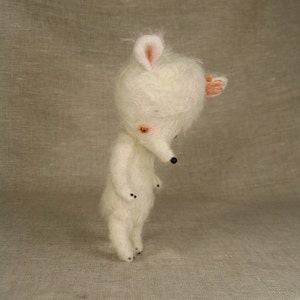 Puede incluir: Un juguete de peluche blanco con un hocico largo y orejas grandes. El juguete tiene ojos negros y una nariz negra. El juguete est&aacute; de pie sobre una superficie marr&oacute;n claro.