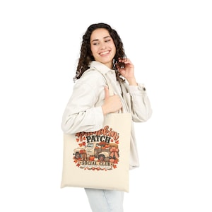 Peut inclure: Un sac fourre-tout en toile couleur crème avec une impression graphique représentant un camion vintage rempli de citrouilles et de feuilles d'automne. Le texte indique Pumpkin Patch Social Club, Coffee, Hay Rides, Fall Vibes, avec des motifs écossais.