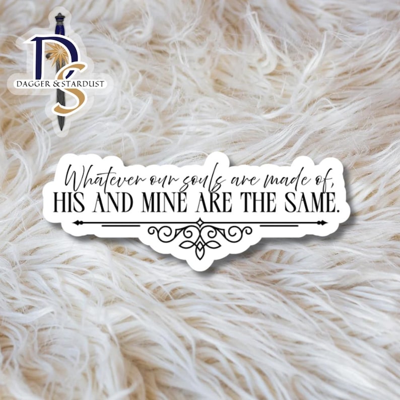Puede incluir: Una pegatina blanca con la frase "Whatever our souls are made of, HIS AND MINE ARE THE SAME." en negro. La pegatina tiene un borde negro y un adorno decorativo. Sobre un fondo blanco y esponjoso.