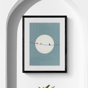 Pode incluir: Uma impressão emoldurada de uma ilustração minimalista de quatro pássaros empoleirados em um fio na frente de um grande círculo branco sobre um fundo azul claro. Uma pequena planta suculenta em vaso está em uma prateleira branca abaixo da impressão.