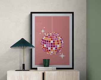 May include: A framed poster with a pink background and a disco ball hanging from the ceiling. The disco ball is made of mirrored tiles in shades of pink, orange, and white. There are two small white stars on either side of the disco ball. The poster is sitting on a light wood shelf with two books and a green glass.