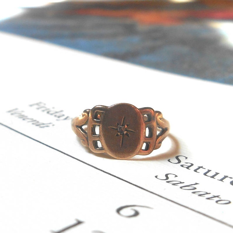 Puede incluir: Un anillo de oro con un dise&ntilde;o decorativo y un peque&ntilde;o diamante en el centro.