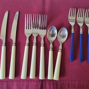 May include: A set of silverware with white and blue handles. The set includes four forks, two knives, and two spoons.