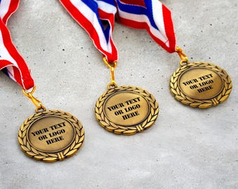 Peut inclure: Trois médailles de bronze avec des bordures de couronne de laurier et des rubans rouges, blancs et bleus. Chaque médaille porte le texte "YOUR TEXT OR LOGO HERE" en noir, parfaites pour la personnalisation. Les médailles sont sur une surface grise.