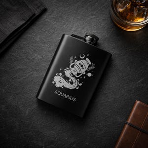 May include: A black stainless steel hip flask with an engraved Aquarius zodiac design. The flask displays the Aquarius symbol, including a water bearer, stars, and the word "Aquarius".