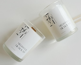 May include: Two clear glass candle jars with white labels. The labels have the date "27 09 24" and the names "Melissa & Nicholas".