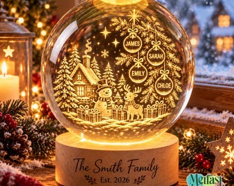 Op de afbeelding: Een bolvormig glazen ornament met een inwendige lasergeëtste winterscène met een hut, sneeuwpop, rendier en cadeaus. Vier hangende ornamenten zijn gegraveerd met de namen James, Sarah, Emily en Chloe. De houten voet vermeldt The Smith Family Est. 2026.