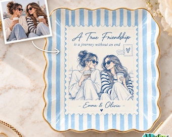 Op de afbeelding: Een vierkant keramieken schaaltje met geschulpte randen en een lichtblauw met wit gestreepte rand. Het midden toont een postzegelontwerp met een illustratie van twee personen met koffiebekers, de tekst A True Friendship is a journey without an end en de namen Emma & Olivia.