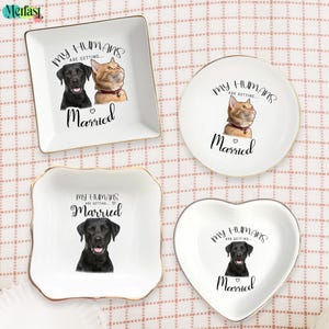 May include: Four white ceramic ring dishes with gold trim. Each dish features a different design: a square dish with a dog and cat, a round dish with a cat, a square dish with a dog, and a heart-shaped dish with a dog. The text "My Humans Are Getting... Married" is written on each dish.