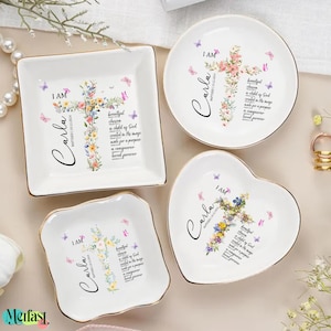 May include: Four white ceramic trinket dishes in square, round, heart, and square shapes. Each dish features a floral cross design, the name "Carla", and the text "I AM". Gold trim edges the dishes.