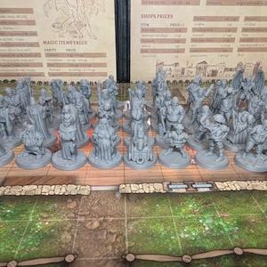 May include: A selection of grey miniature figurines, possibly for a tabletop game, arranged on a game board. The figurines represent various characters, including figures with staffs and cloaks. The game board has a green and brown grid pattern.