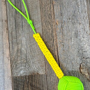 May include: A yellow and green paracord dog toy with a knotted ball at the end and a loop handle.